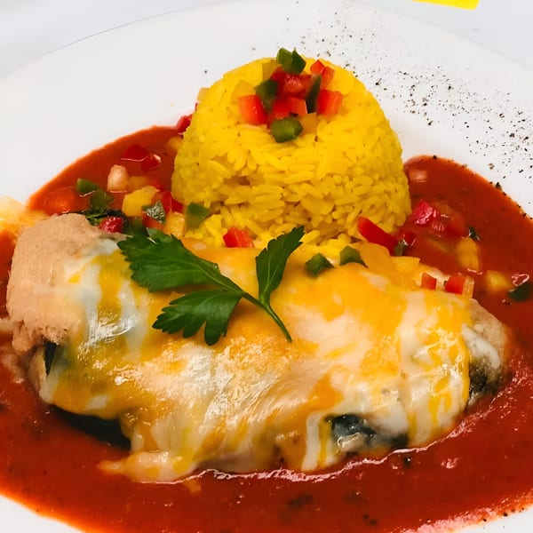 Peruvian dish with a cheese-covered chili relleno, yellow rice, and red sauce on a white plate.