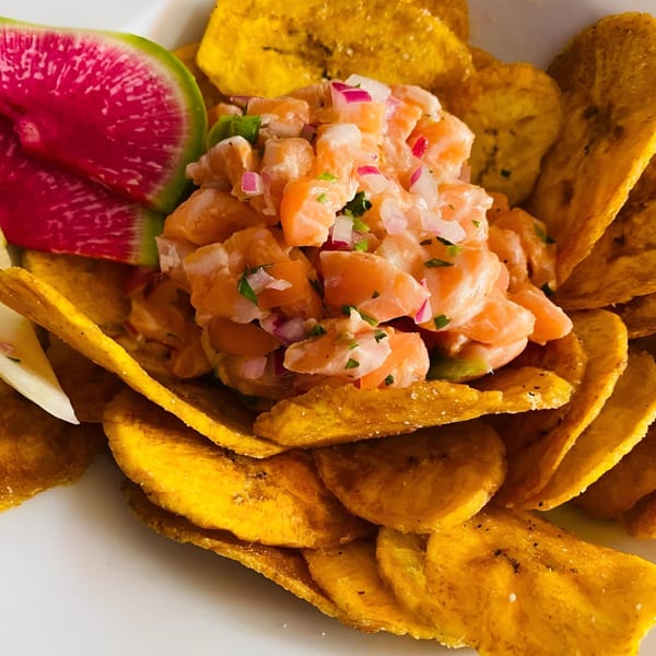 Peruvian salmon ceviche with red onion, cilantro, and plantain chips, garnished with watermelon radish.
